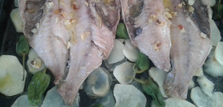 Dentón con patatas y pimientos preparado para el horno